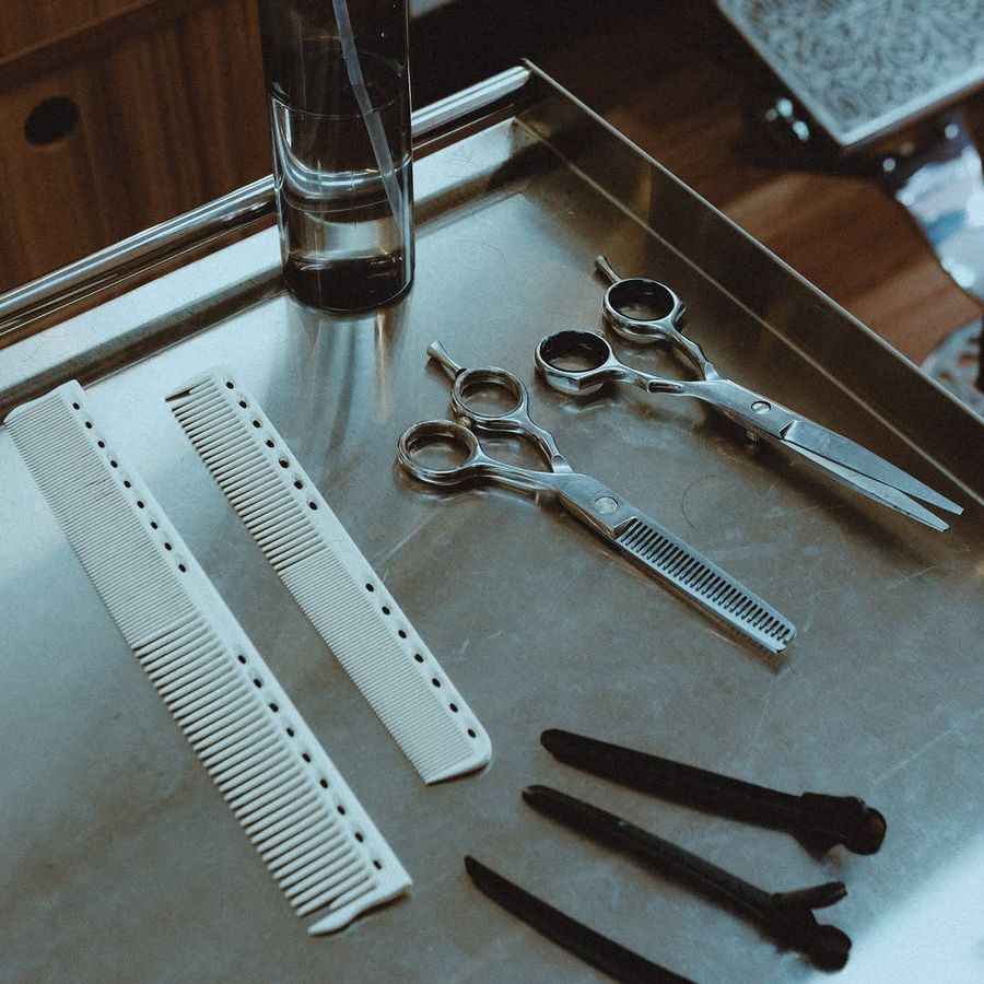 Tesouras, pentes e presilhas sobre bandeja de inox